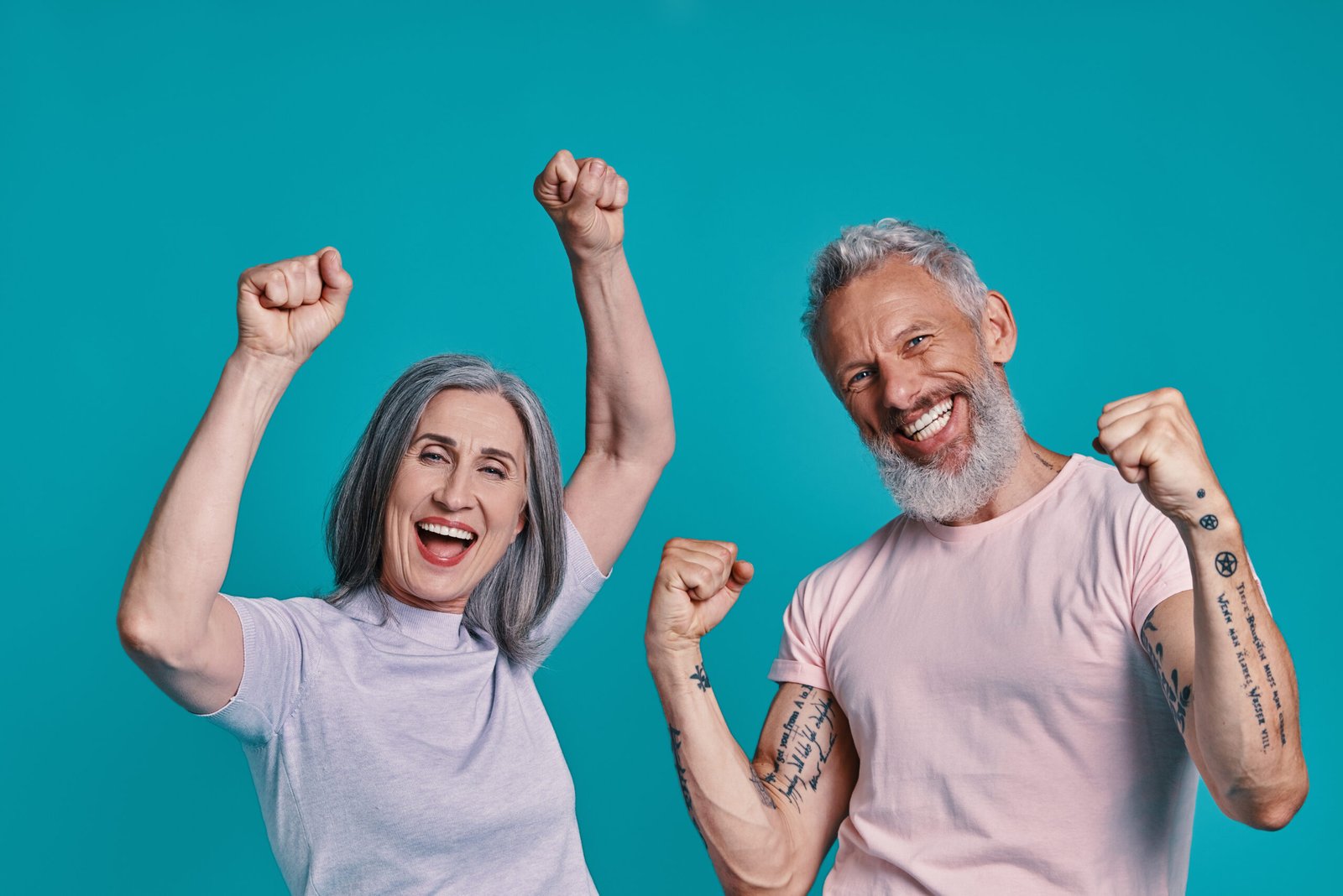 Happy senior couple looking at camera and gesturing while standing together against blue background